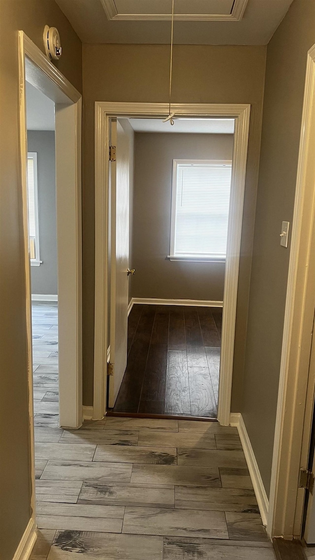 hall with baseboards, wood finished floors, and attic access