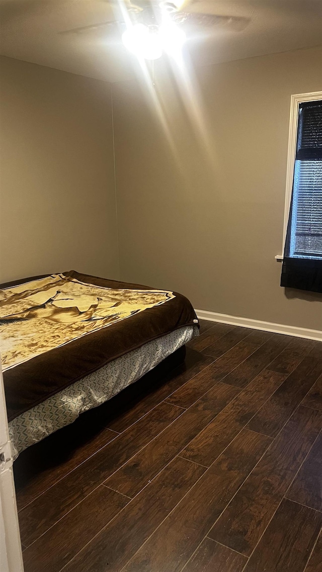 unfurnished bedroom with dark wood-style flooring, baseboards, and ceiling fan