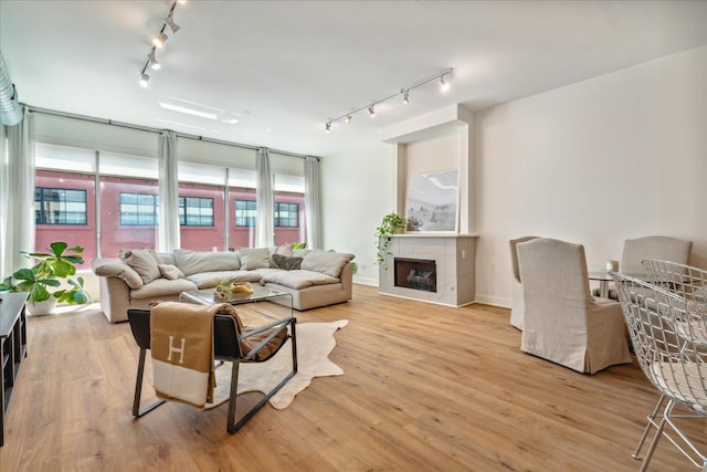 living room with light wood-type flooring, a tile fireplace, and track lighting