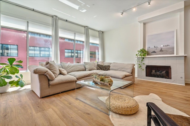 living room featuring light hardwood / wood-style flooring, a tile fireplace, and track lighting