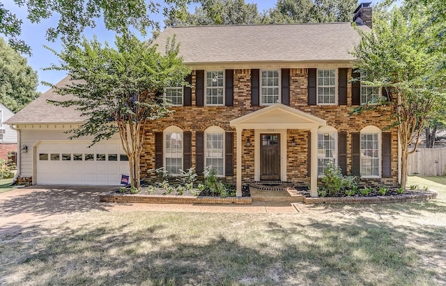 colonial-style house featuring a garage and a front yard