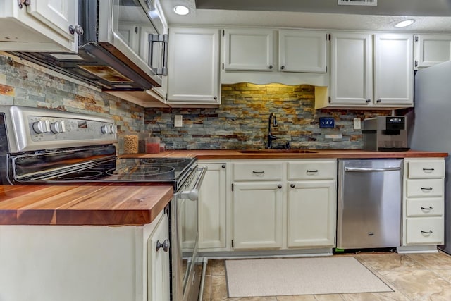 kitchen with stainless steel appliances, a sink, white cabinets, wooden counters, and tasteful backsplash