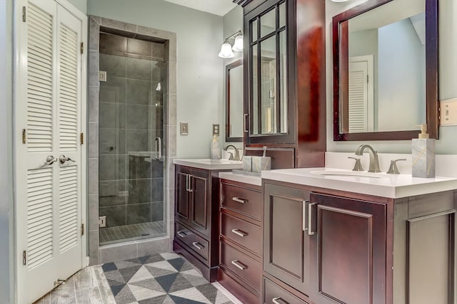 full bath with a closet, two vanities, a sink, and a stall shower