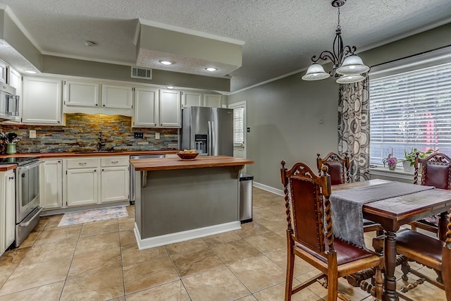 kitchen with light tile patterned floors, backsplash, stainless steel appliances, and plenty of natural light