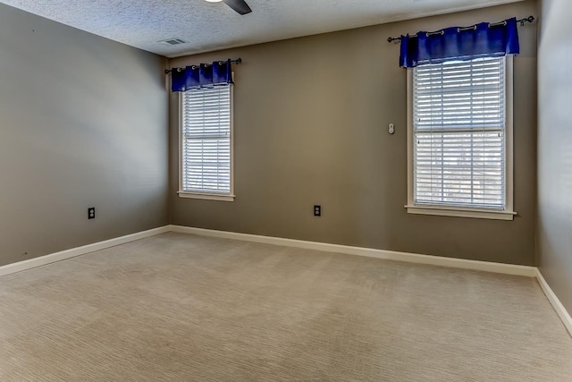 carpeted empty room featuring baseboards, plenty of natural light, visible vents, and a textured ceiling