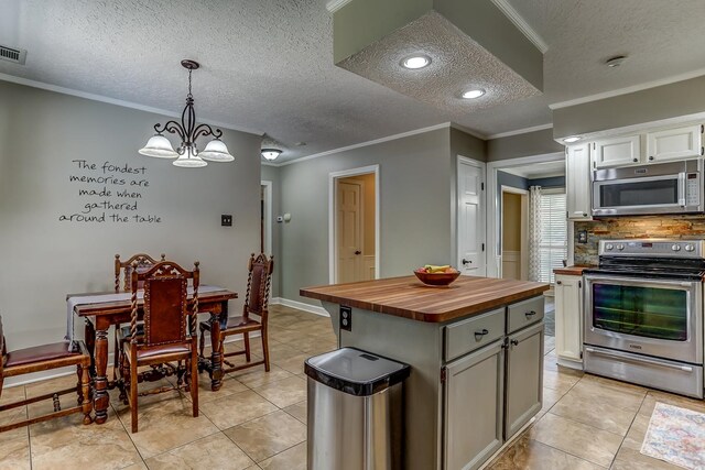 kitchen with appliances with stainless steel finishes, a center island, a notable chandelier, and ornamental molding