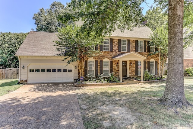 colonial house with brick siding, a shingled roof, concrete driveway, fence, and a garage