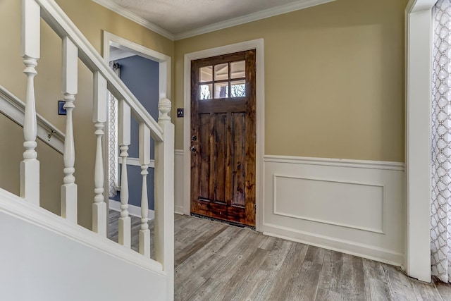 entrance foyer featuring stairs, ornamental molding, wainscoting, and wood finished floors