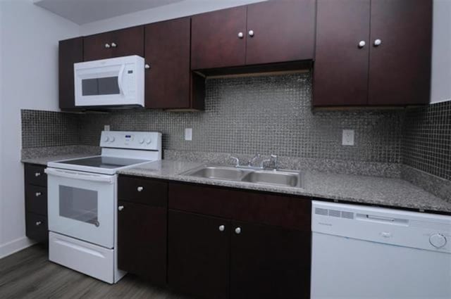 kitchen with tasteful backsplash, white appliances, light countertops, a sink, and wood finished floors