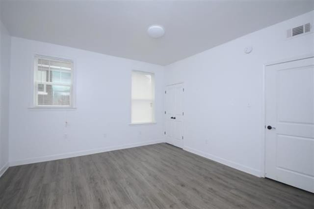spare room with visible vents, baseboards, and wood finished floors