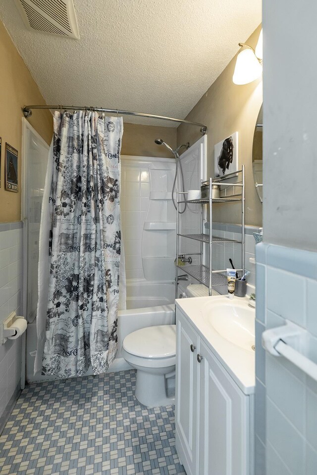 full bathroom featuring vanity, toilet, tile patterned floors, and a textured ceiling