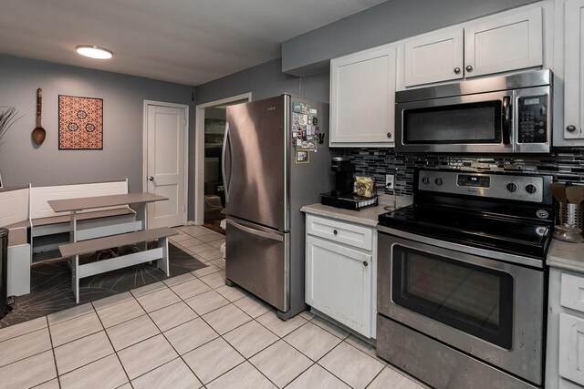 kitchen with tasteful backsplash, light tile patterned floors, stainless steel appliances, and white cabinetry