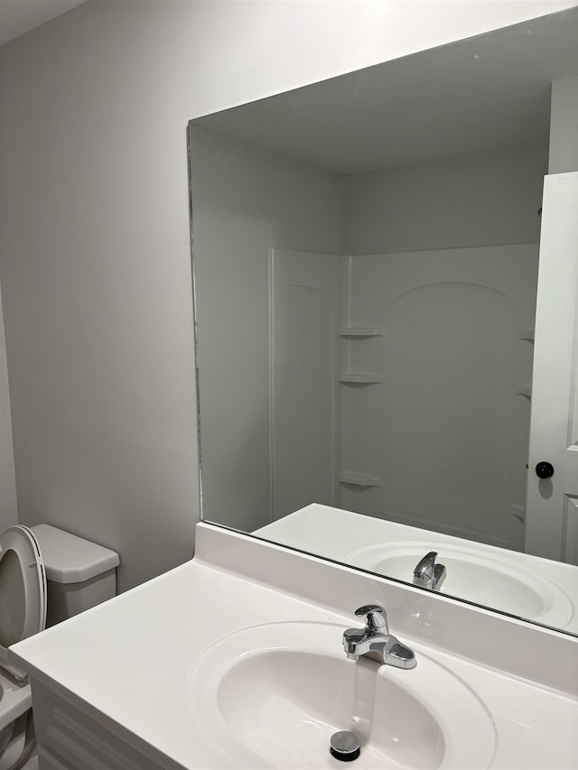 bathroom with walk in shower, vanity, and toilet