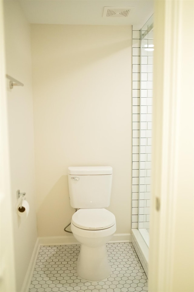 bathroom featuring toilet, tile patterned flooring, visible vents, and a tile shower