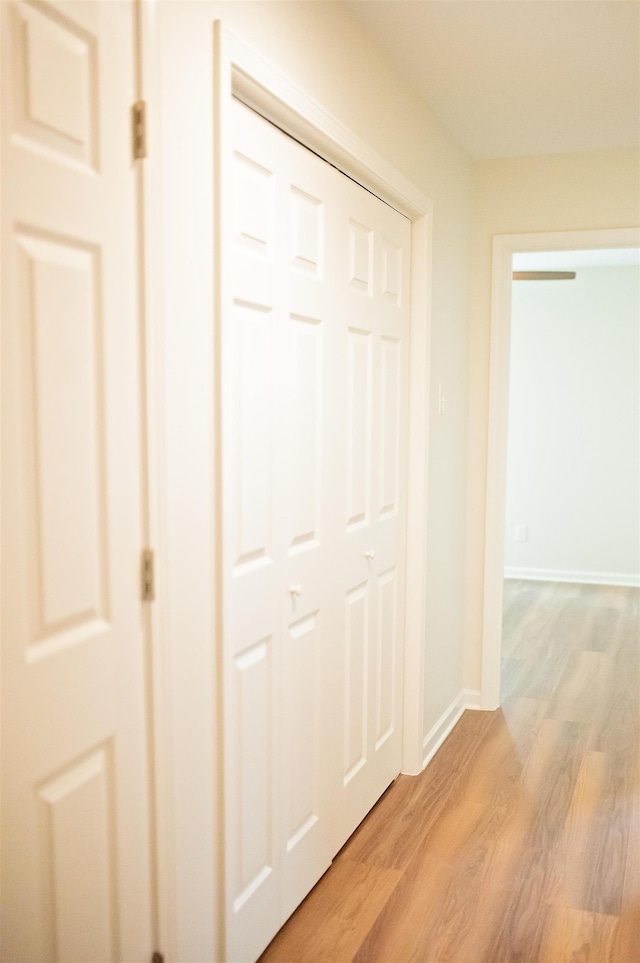 hall with light wood-style floors and baseboards