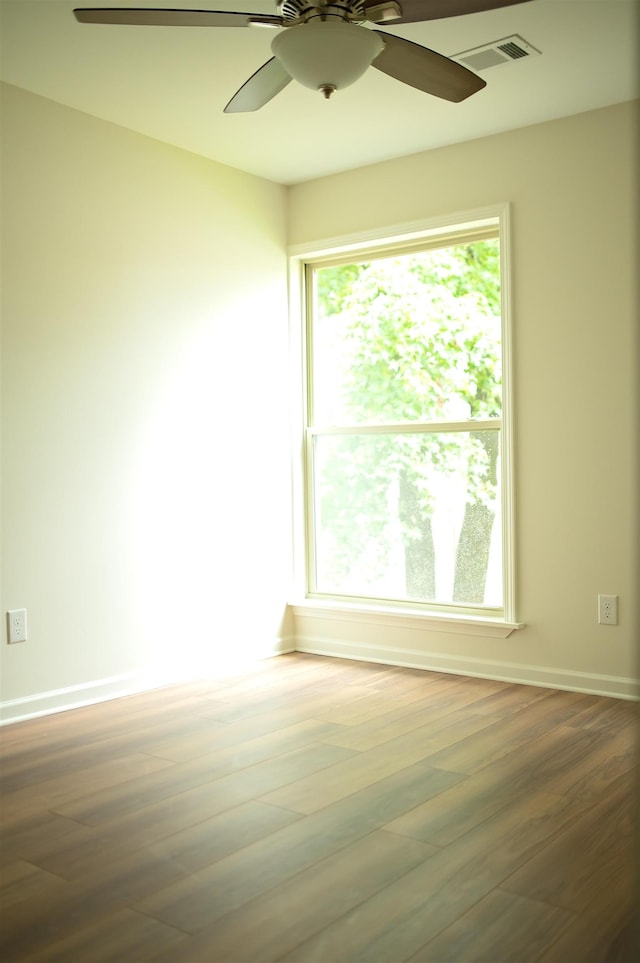 unfurnished room featuring a ceiling fan, visible vents, baseboards, and wood finished floors