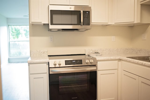 kitchen with white cabinets, appliances with stainless steel finishes, and light countertops