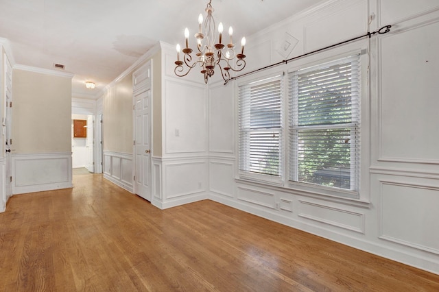 unfurnished dining area with a notable chandelier, crown molding, and light hardwood / wood-style floors