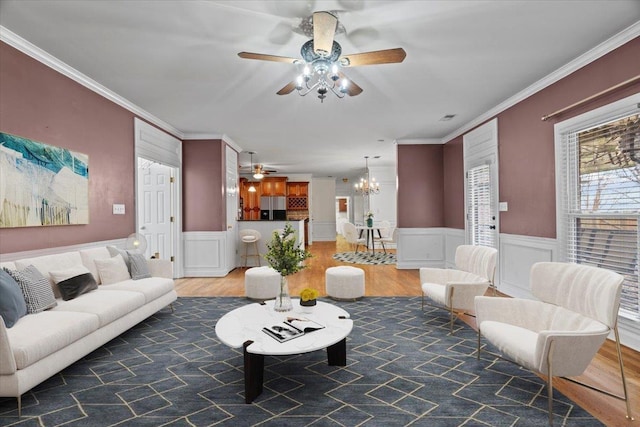 living area with ornamental molding, a wainscoted wall, and wood finished floors