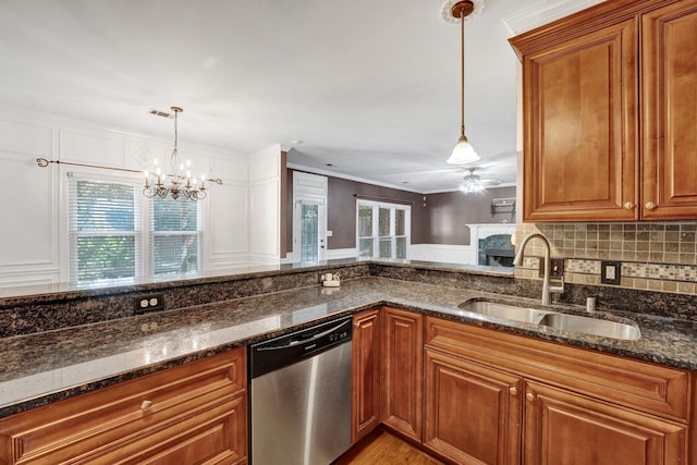 kitchen with sink, dark stone counters, stainless steel dishwasher, and pendant lighting