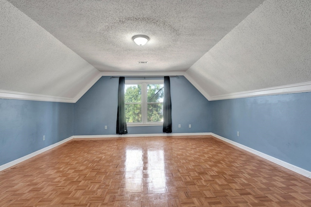 additional living space featuring parquet flooring, a textured ceiling, and lofted ceiling