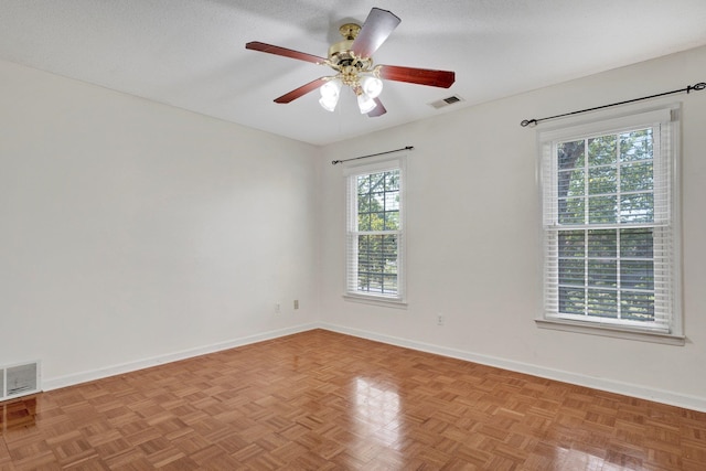 empty room with a textured ceiling, ceiling fan, and light parquet floors