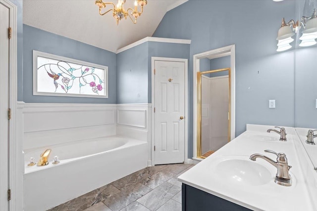 bathroom with wainscoting, lofted ceiling, a garden tub, a shower stall, and a sink