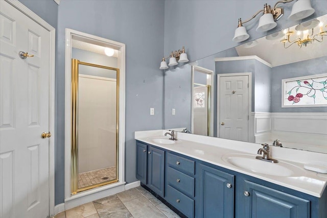 bathroom featuring a wainscoted wall, double vanity, a sink, and a shower stall