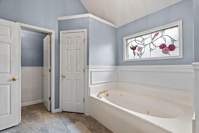 bathroom featuring lofted ceiling, wainscoting, and a garden tub