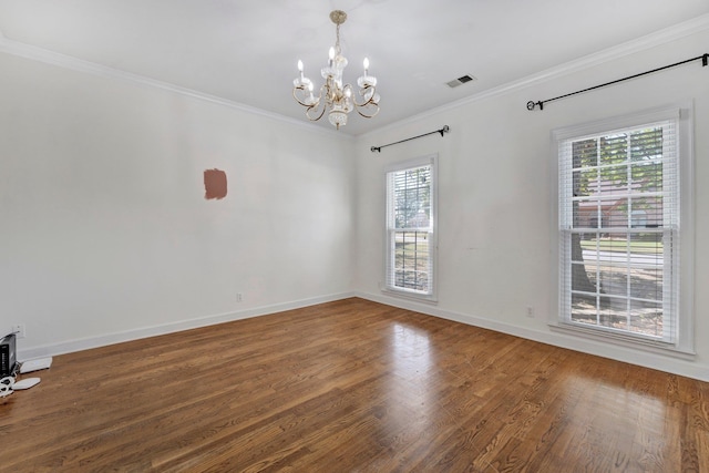 empty room with plenty of natural light, a chandelier, ornamental molding, and hardwood / wood-style flooring