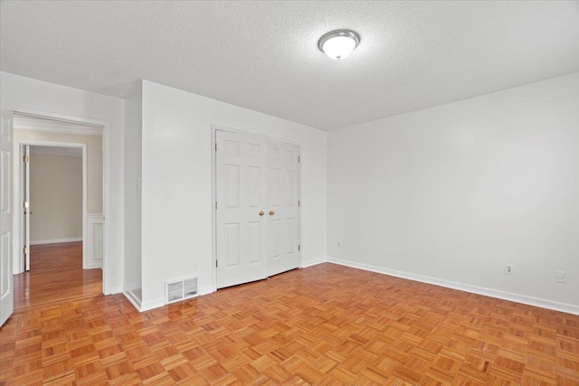 unfurnished bedroom featuring a textured ceiling, a closet, visible vents, and baseboards