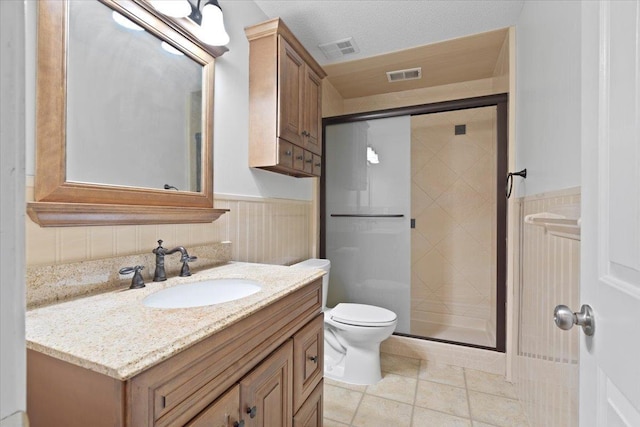 full bathroom with visible vents, toilet, a stall shower, wainscoting, and vanity