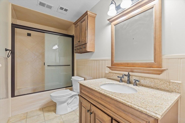 bathroom featuring visible vents, toilet, a wainscoted wall, shower / bath combination with glass door, and vanity