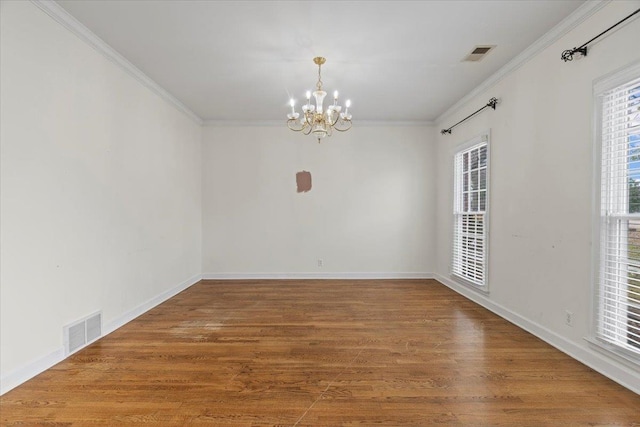 unfurnished room featuring an inviting chandelier, visible vents, wood finished floors, and ornamental molding