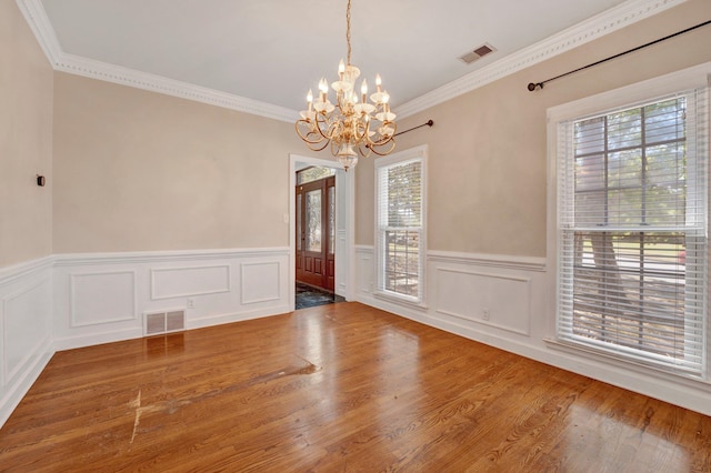 spare room with hardwood / wood-style flooring, an inviting chandelier, and ornamental molding