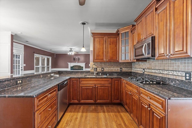 kitchen with a peninsula, appliances with stainless steel finishes, brown cabinetry, and a sink