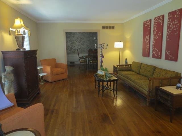 living area with dark wood-type flooring, visible vents, and crown molding