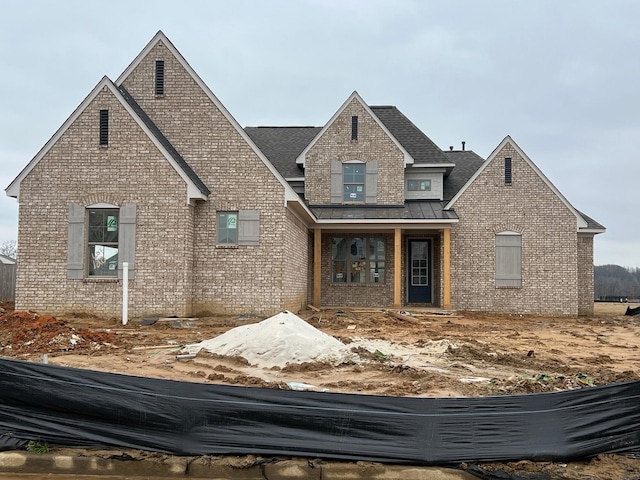 traditional home with a standing seam roof, a shingled roof, metal roof, and brick siding