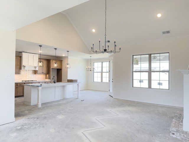 kitchen with a center island with sink, visible vents, open floor plan, a notable chandelier, and a sink