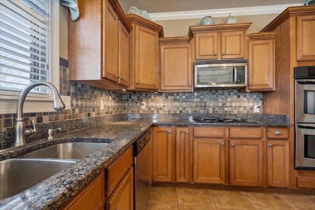 kitchen with backsplash, ornamental molding, light tile patterned floors, sink, and stainless steel appliances