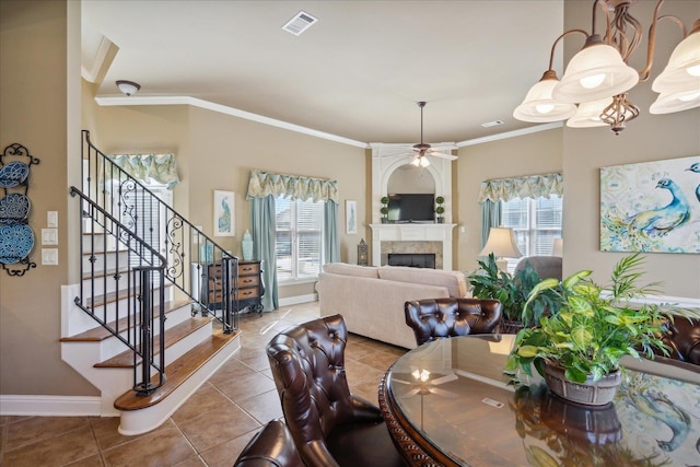 tiled dining area with ceiling fan, plenty of natural light, a tiled fireplace, and crown molding