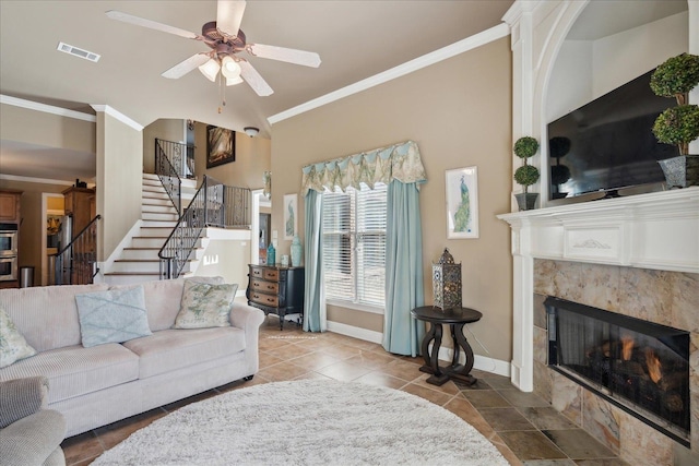 tiled living room with a fireplace, ceiling fan, and crown molding