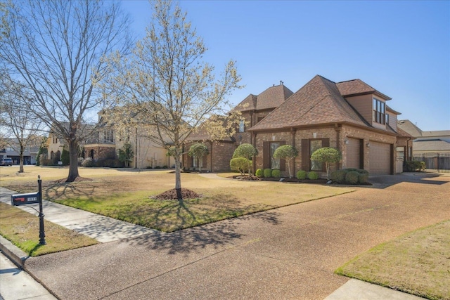 view of front facade featuring a shingled roof, brick siding, driveway, and a front lawn