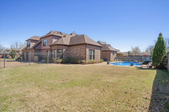 rear view of house with a lawn and a fenced in pool