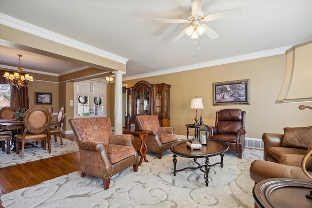 living room with ceiling fan with notable chandelier, decorative columns, crown molding, and hardwood / wood-style floors