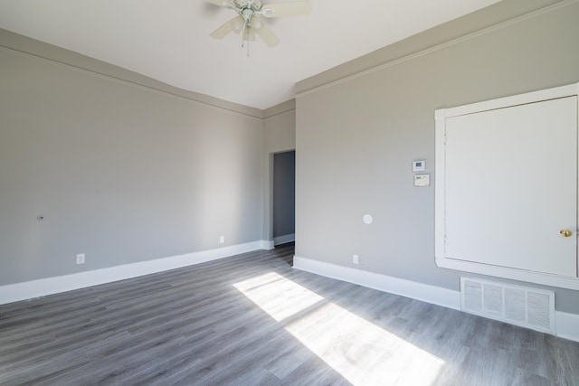 empty room featuring visible vents, baseboards, ornamental molding, wood finished floors, and a ceiling fan