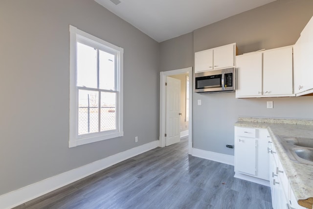 kitchen with light stone counters, white cabinets, and light wood-type flooring