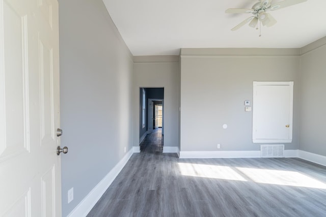 empty room featuring a ceiling fan, wood finished floors, visible vents, and baseboards