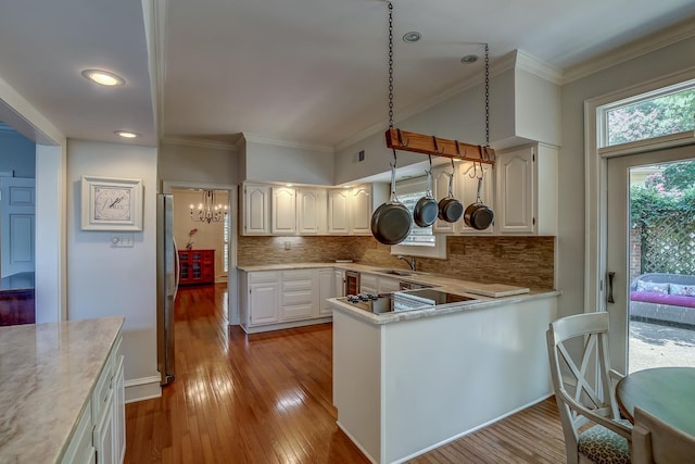 kitchen featuring a peninsula, white cabinets, light countertops, and freestanding refrigerator