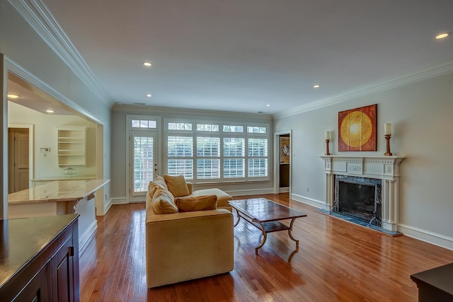 living room with baseboards, a premium fireplace, wood finished floors, and crown molding